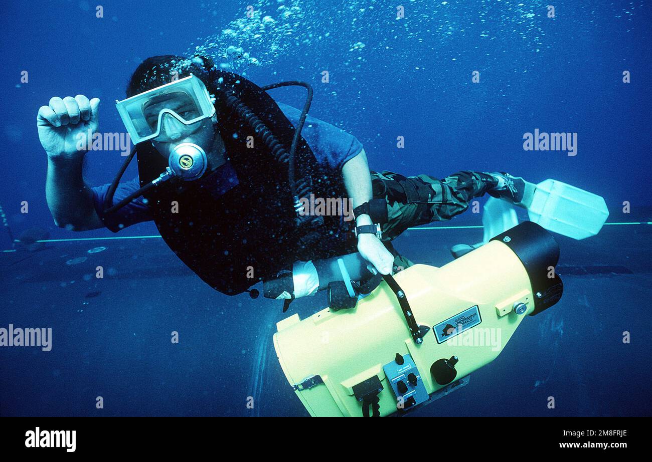 Photographer's Mate (Diver) 2nd Class Greg Slater signals to another diver before surfacing. Slater is on hand to videotape members of a Navy Sea-Air-Land (SEAL) team as they practice entering and leaving a submerged submarine. Country: Unknown Stock Photo