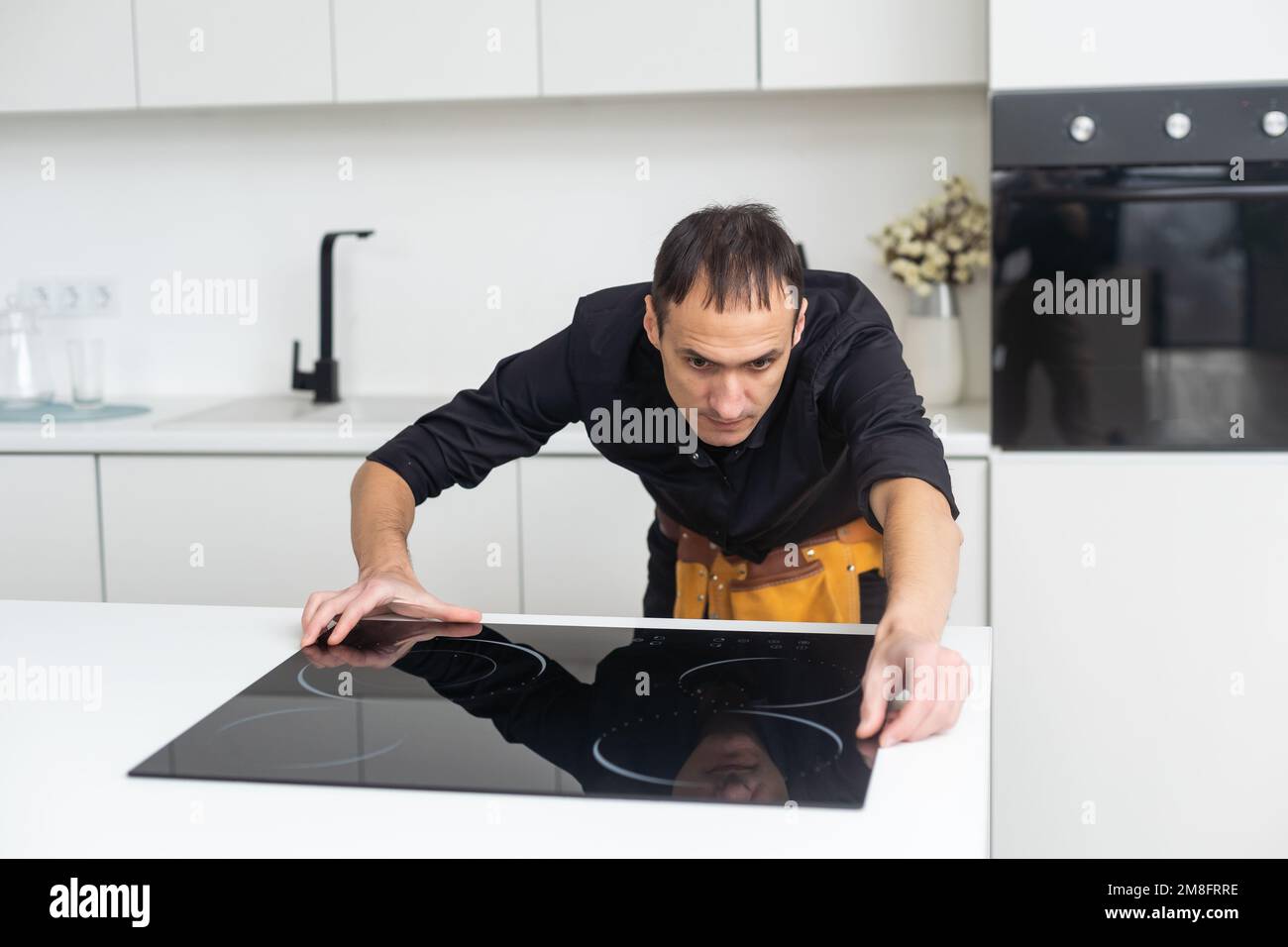 Man electrical repairs kitchen surface apartment. Installing hob in