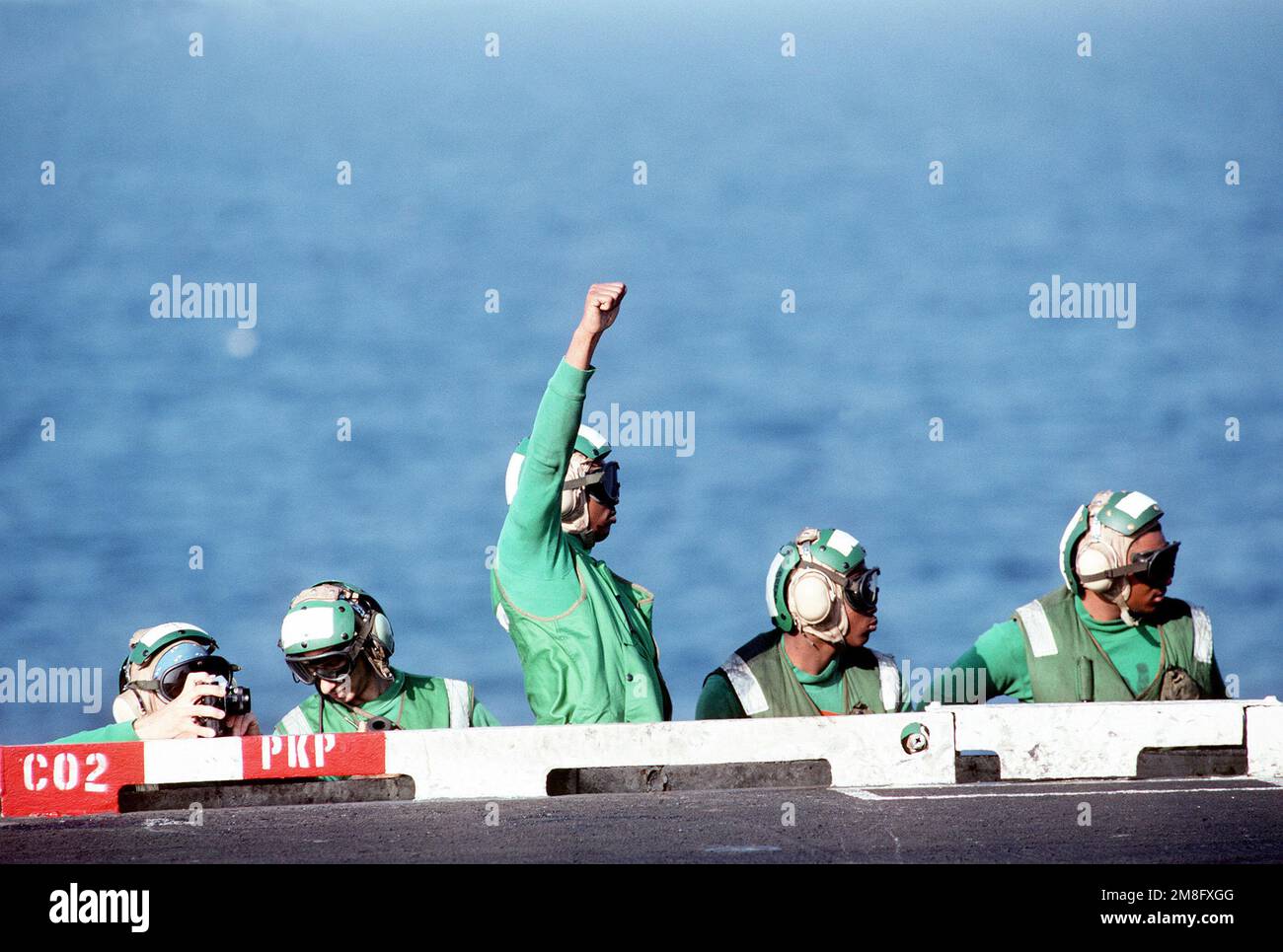 A bow safety crewman gives the "all clear" signal to a catapult officer ...