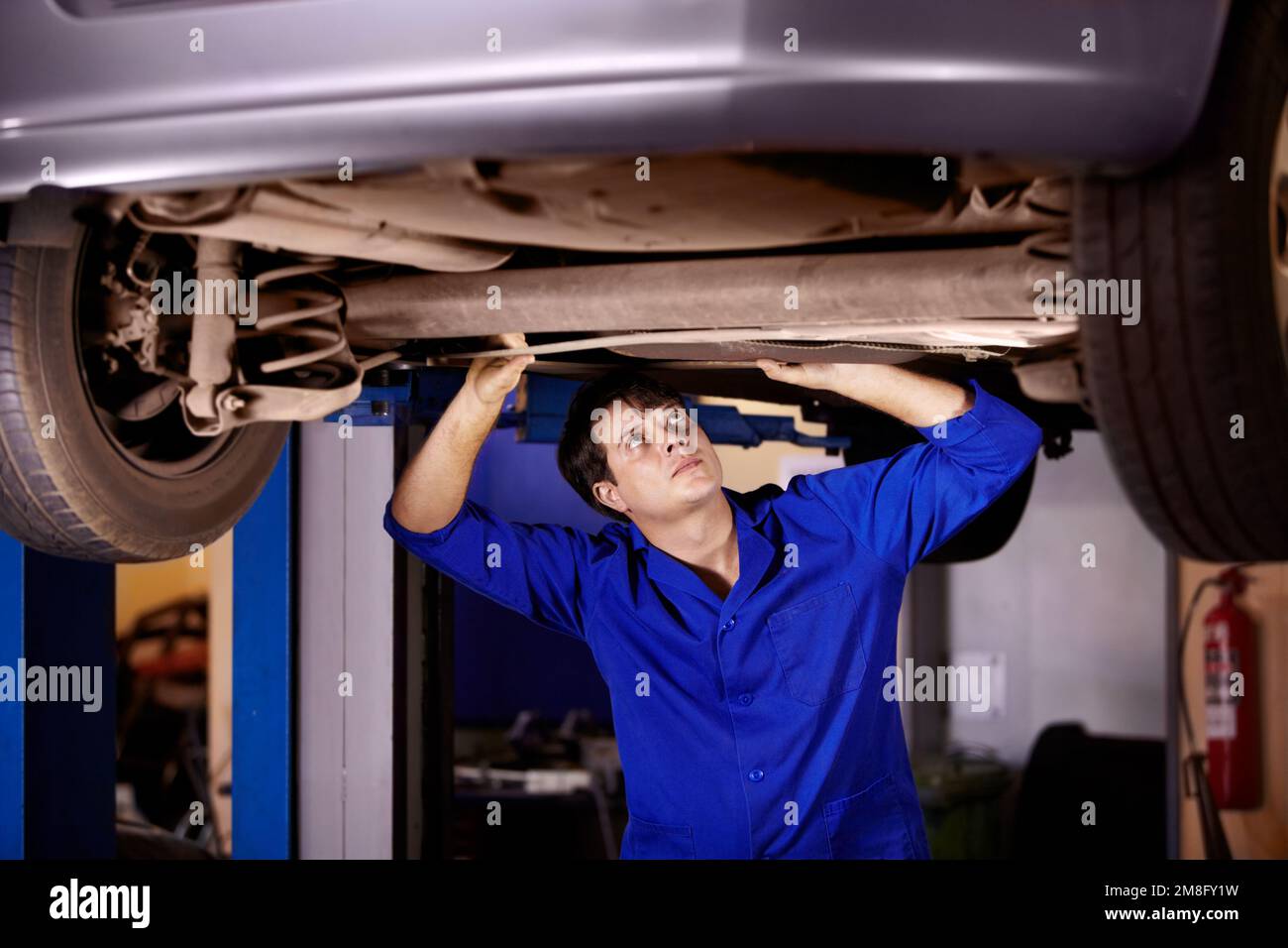 This steering column is a bit bent. A young male mechanic looking at