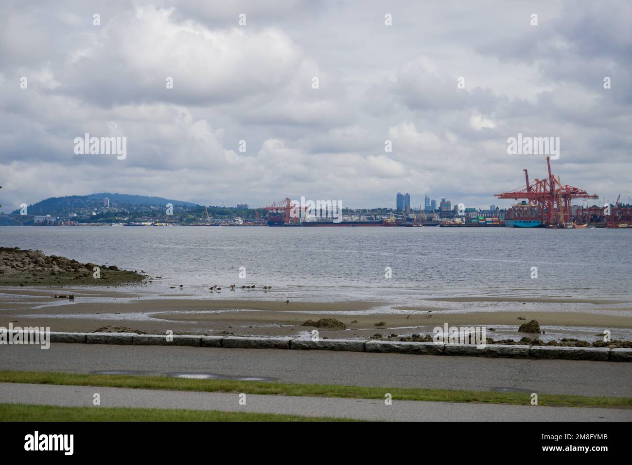 North Vancouver - mountains, bay, Cargo warehouse - industrial port, cargo ship. beautiful clouds and the sea. Travel in the summer. Stock Photo