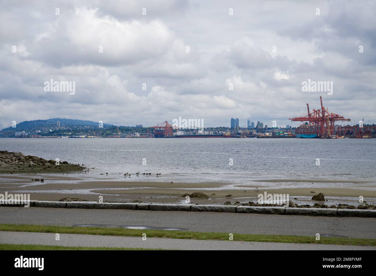 North Vancouver - mountains, bay, Cargo warehouse - industrial port, cargo ship. beautiful clouds and the sea. Travel in the summer. Stock Photo