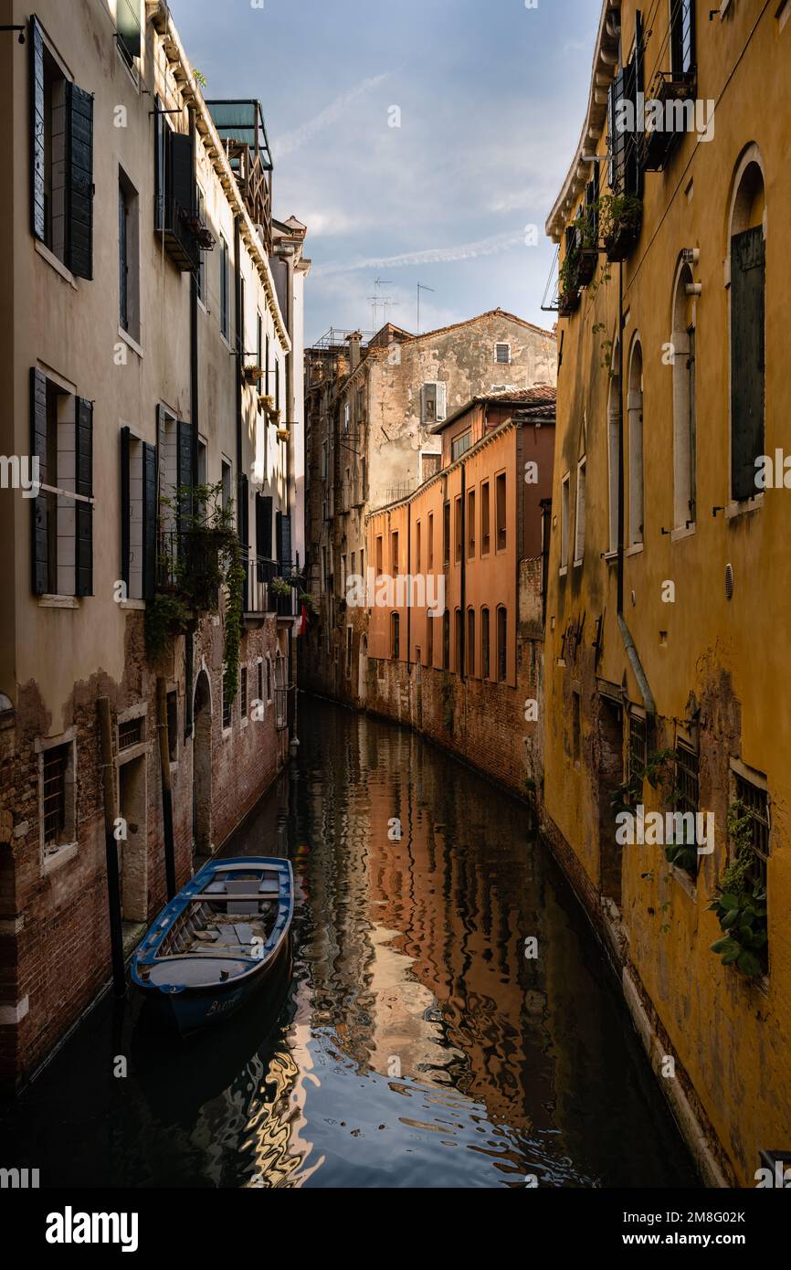 Small Canal with Moored Boat in Venice, Italy with Romantic old Houses Stock Photo