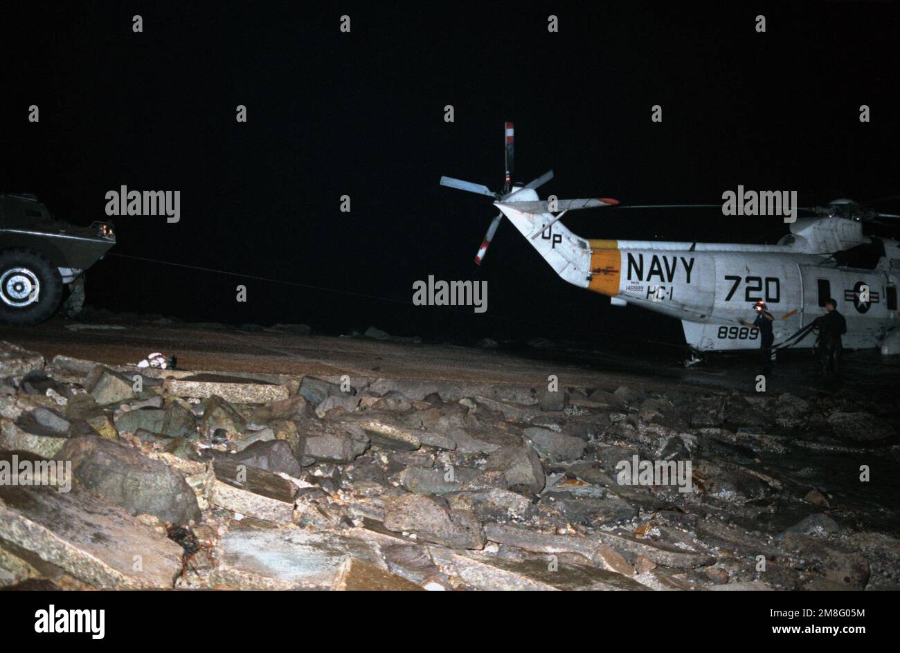 Night shot of recovery operations of a US Navy (USN) SH-3G Sea King from the Helicopter Combat Support Squadron 1 (HC-1) 'Fleet Angels,' NAS North Island, California, that crash landed in the water. Marine and Navy personnel begin to tow the aircraft ashore. Country: Unknown Stock Photo