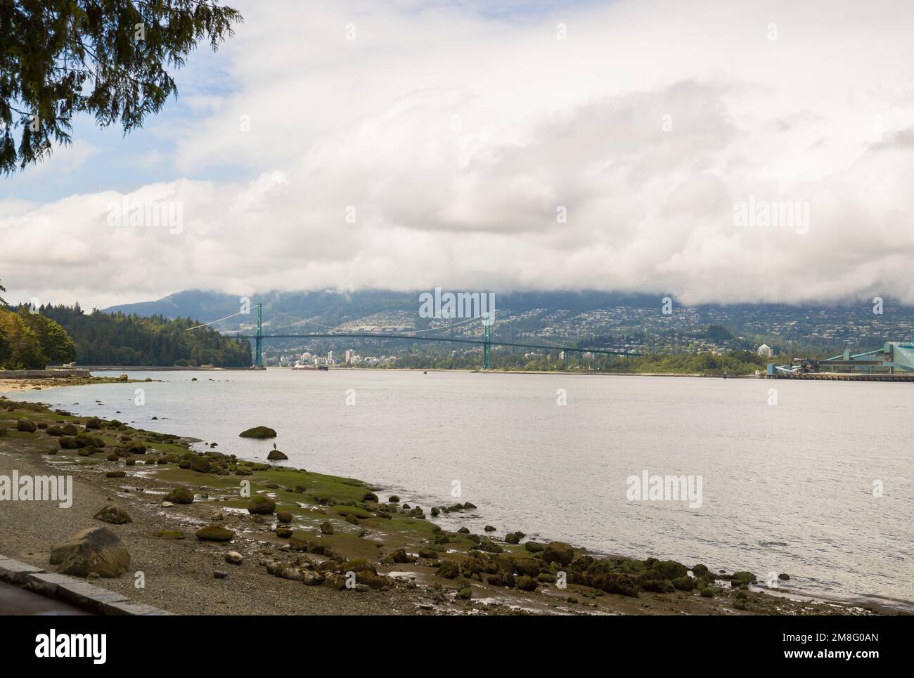 North Vancouver - mountains, bay, Cargo warehouse - industrial port, cargo ship. beautiful clouds and the sea. Travel in the summer. Stock Photo