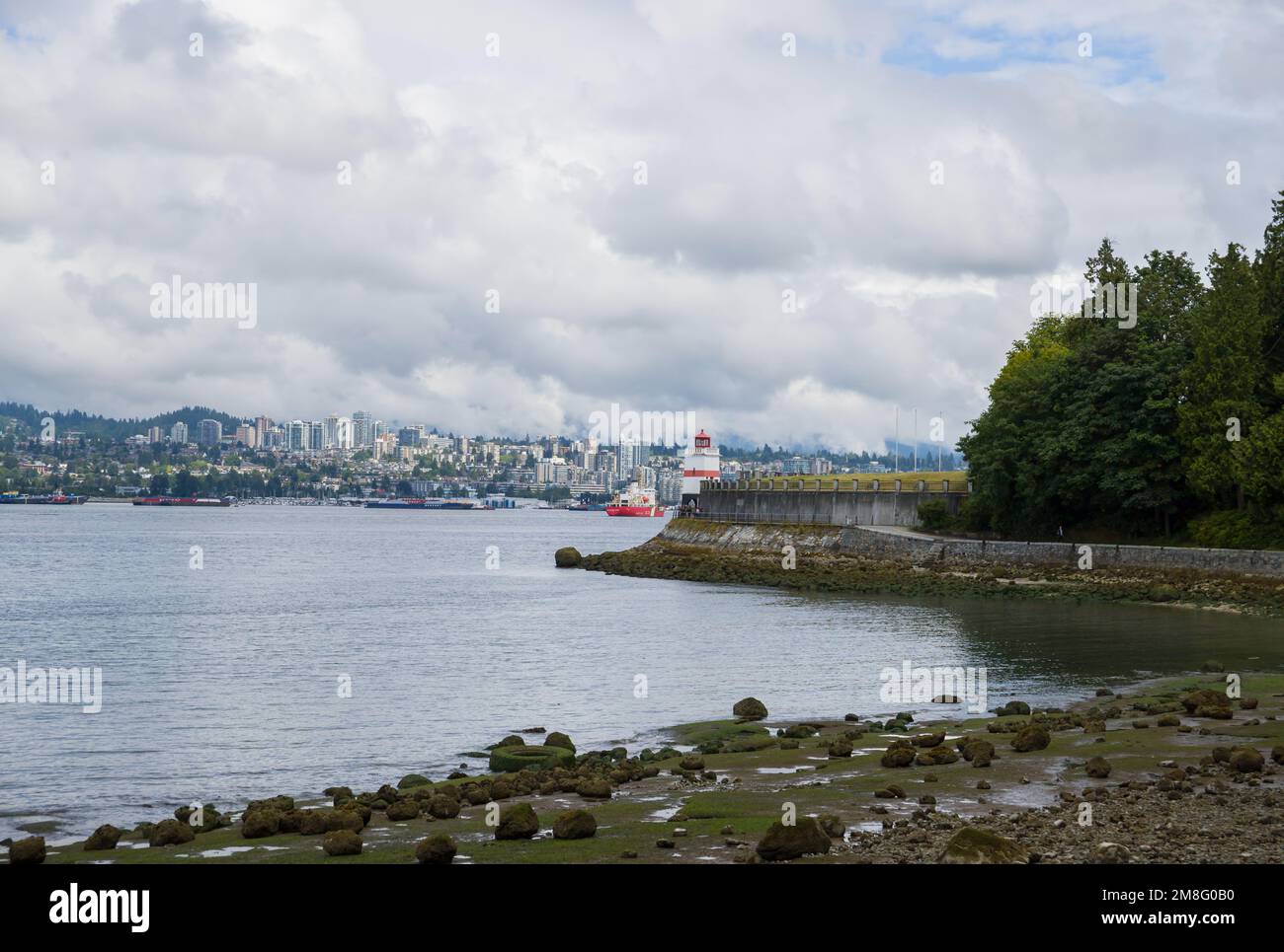 North Vancouver - mountains, bay, Cargo warehouse - industrial port, cargo ship. beautiful clouds and the sea. Travel in the summer. Stock Photo