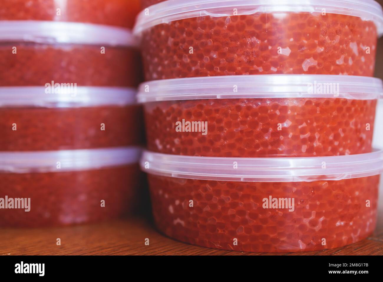 Red caviar plactic jars, rows of salted canned red caviar containers filled to the top on