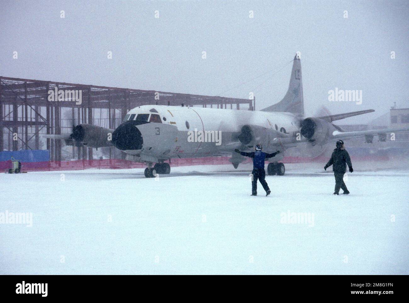 Crewmen direct a P-3 Orion anti-submarine aircraft of Patrol Squadron 11 (VP-11) into position for take-off during a New England snow storm. Base: Naval Air Station, Brunswick State: Maine(ME) Country: United States Of America (USA) Stock Photo