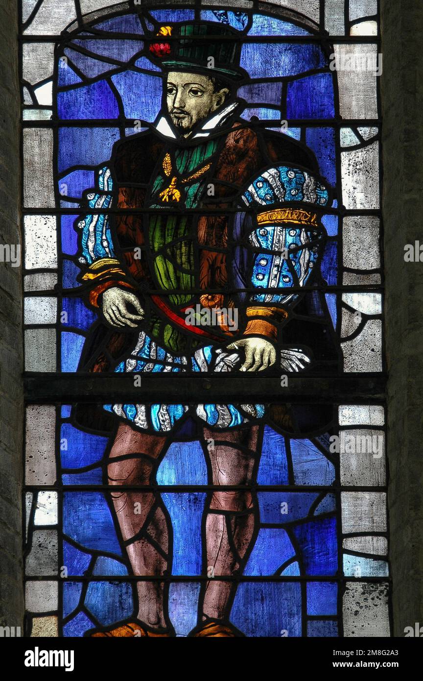 Mid-1900s stained glass window, designed by Joep Nicolas (1897-1972), in the Oude Kerk, Delft, Netherlands.  It depicts a young nobleman in typical Renaissance costume and commemorates William the Silent (1533-1584), Prince of Orange, who led the revolt against Spanish Hapsburg rule that resulted in the Eighty Years’ War and formal independence for the United Provinces in 1648. William became Prince of Orange in 1544 and, as founder of the House of Orange-Nassau, was the ancestor of the present Dutch monarchy. In the Netherlands, he is known as Vader des Vaderlands (Father of the Fatherland). Stock Photo
