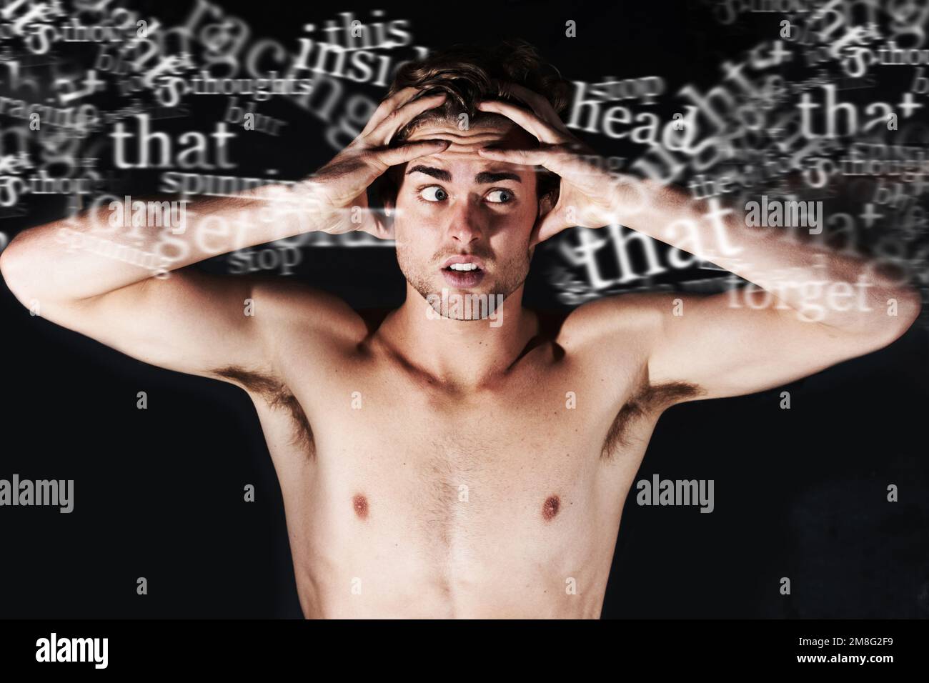 Hes hearing voices. A young man holding his head surrounded by words. Stock Photo