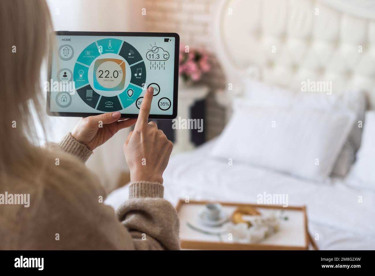 Woman controlling smart home devices using a digital tablet with ...
