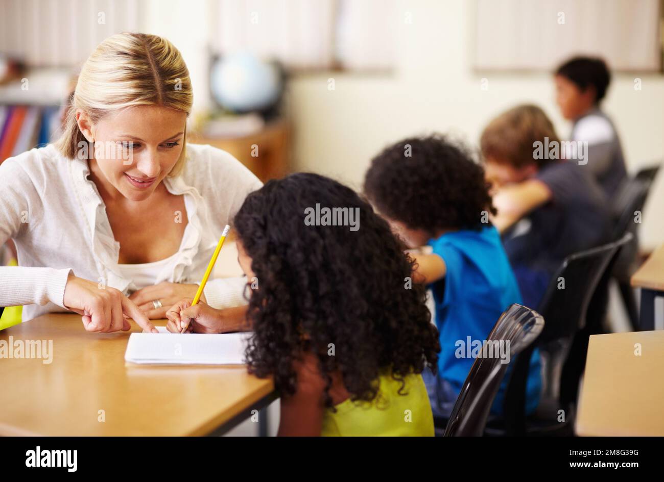 Helping them to understand. A young teacher helping children with their ...