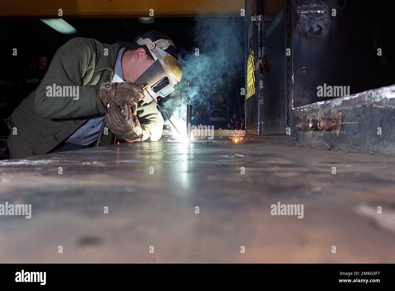 Hull Technician/Fireman Oglialoro wears a welder's mask as he uses an