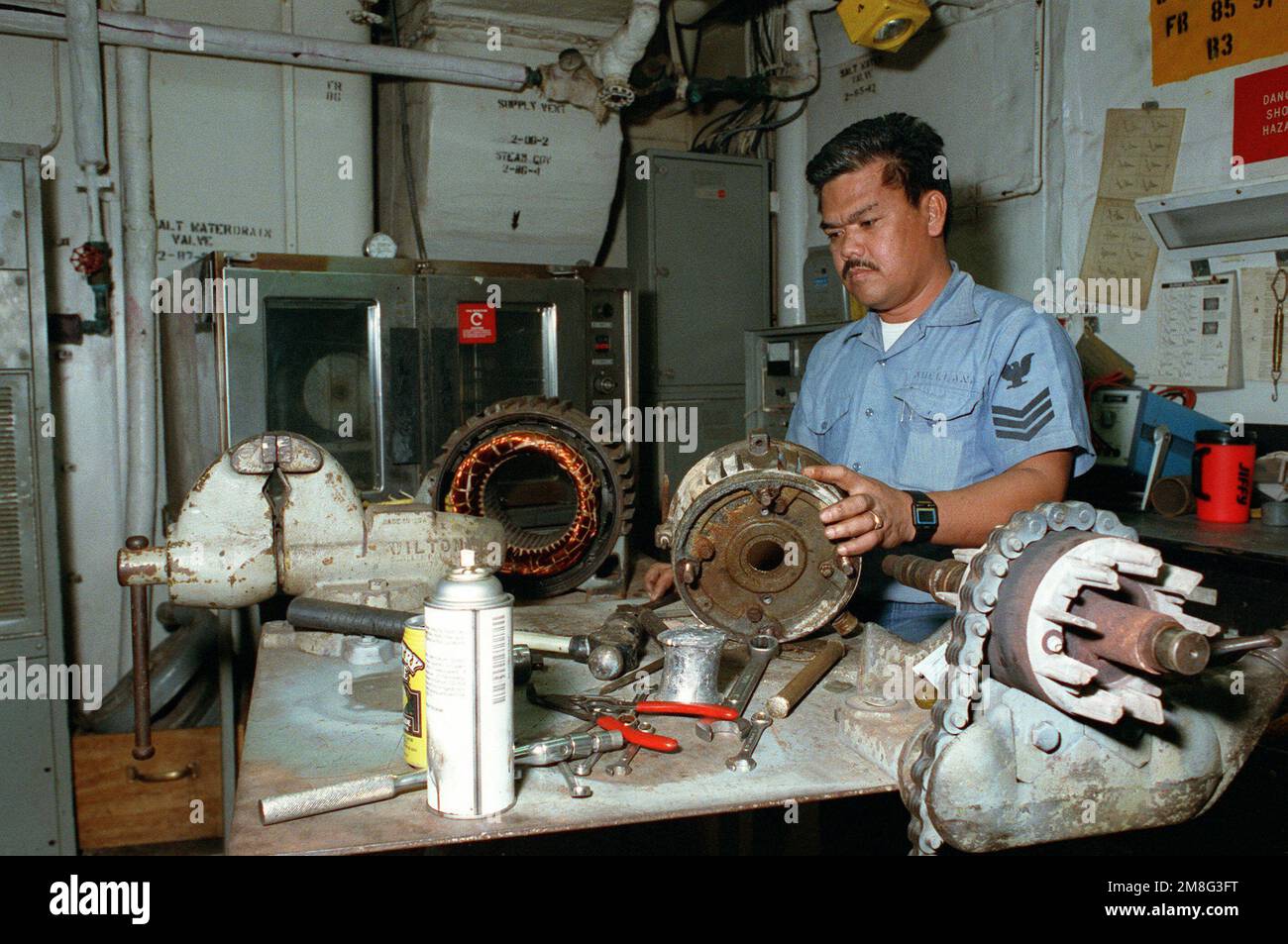 Electrician's Mate 1ST Class R. L. Abellana repairs a motor in the