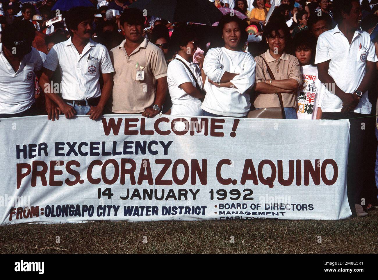 Crowd members display a banner to welcome Philippine President Corazon Aquino as she arrives on base for a visit. Base: Naval Station, Subic Bay State: Luzon Country: Philippines(PHL) Stock Photo