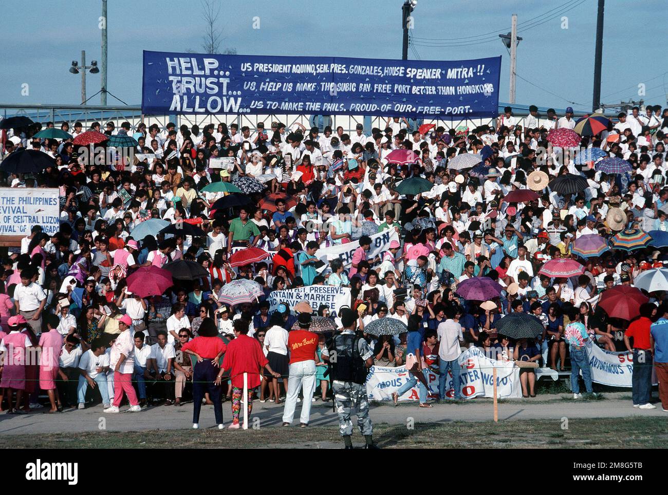 A large banner expresses the Filipino desire for autonomous control of the naval station, scheduled to be turned over to the Philipines later in 1992. Crowd members are gathered to voice their sentiments and greet Philippine President Corazon Aquino, who is visiting the base. Base: Naval Station, Subic Bay State: Luzon Country: Philippines(PHL) Stock Photo