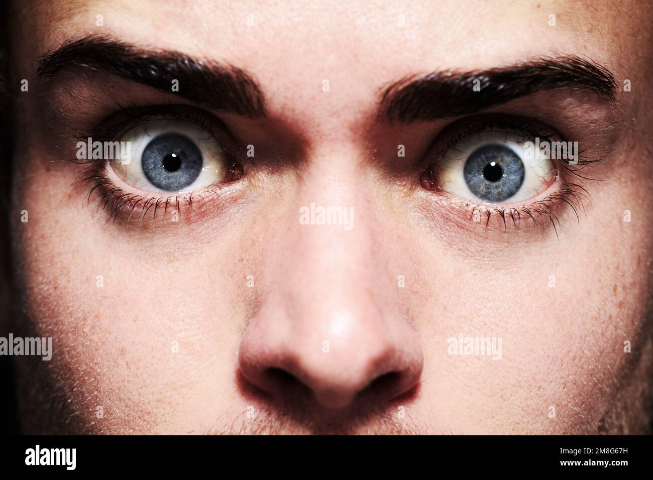 His eyes give away his fear. Closeup portrait of a young man with wide eyes. Stock Photo
