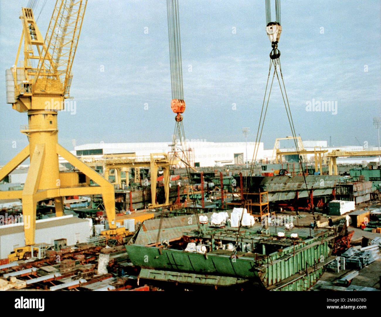 Cranes lift a section of the hull in place as the keel is laid for the