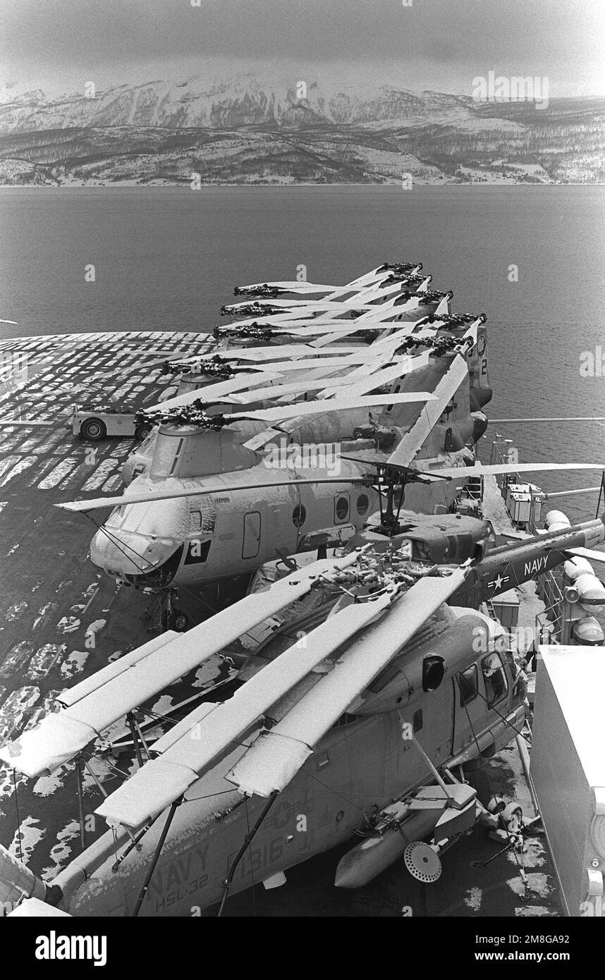 A view of helicopters parked on the fore end of the flight deck of the amphibious assault ship USS GUADALCANAL (LPH-7). In the foreground is a SH-2F Sea Sprite helicopter of Light Helicopter Squadron 32 (HSL-32). Above that is the ship's own helo, a UH-1N Iroquois 'Huey' affectionately known as 'Candy Cane'. Five CH-46E Sea Knight helicopters of Marine Medium Helicopter Squadron 263 (HMM-263) complete the deck spot. The ship is taking part in winter operations as part of NATO Exercise Teamwork '92. Subject Operation/Series: TEAMWORK '92 Base: Trondheim Fjord Country: Norway (NOR) Stock Photo