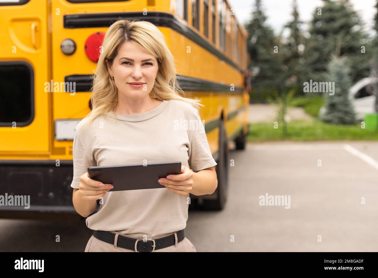 Portrait of cheerful teacher standing near the school bus Stock Photo ...