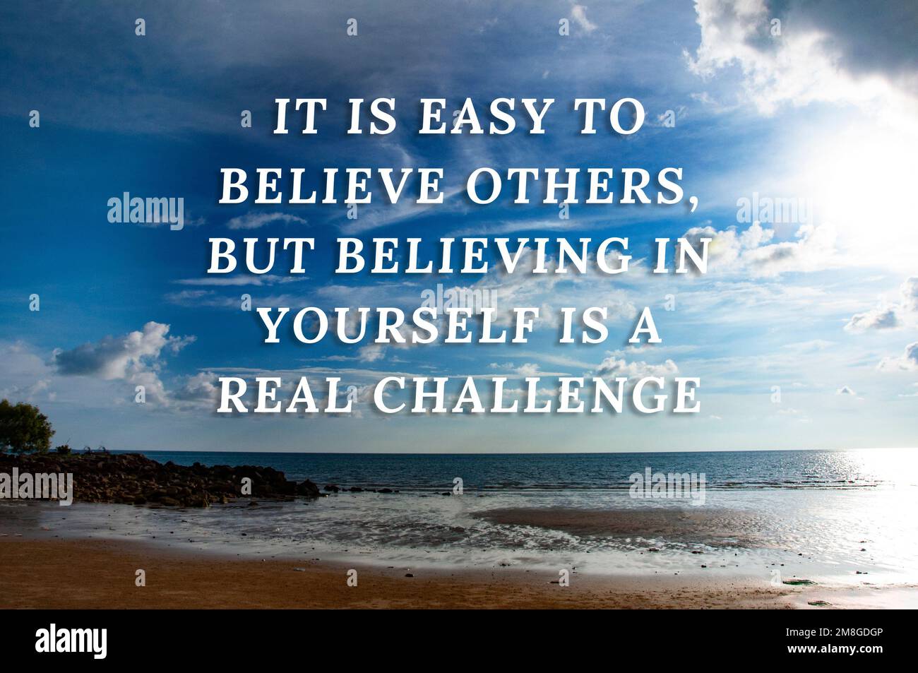 Motivational quotes text - It is easy to believe others, but believing in yourself is a real challenge. With beautiful beach background. Motivational Stock Photo