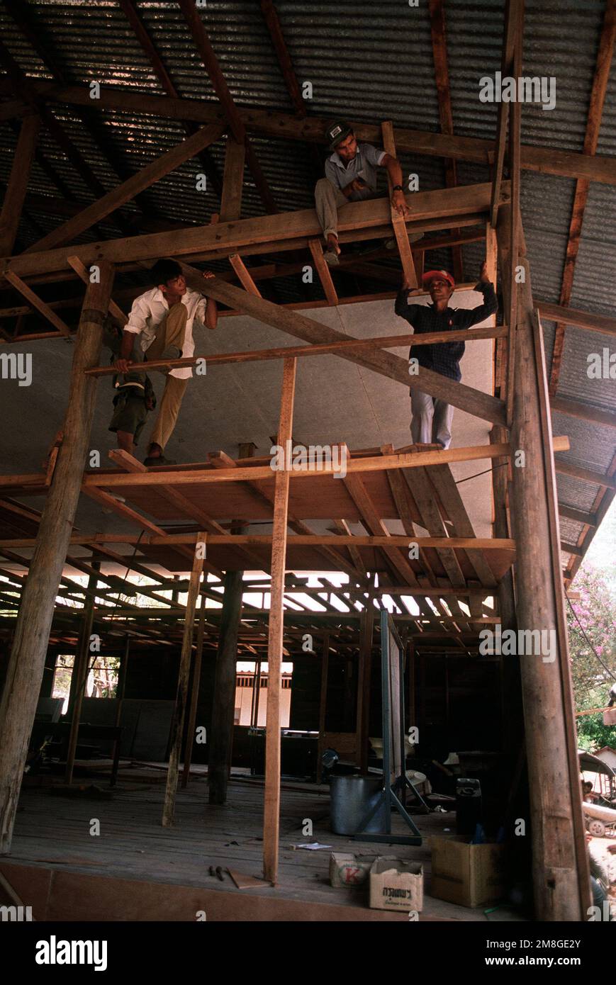 Thai civilians work on the rafters of the Ban Laem Ruek community hall ...