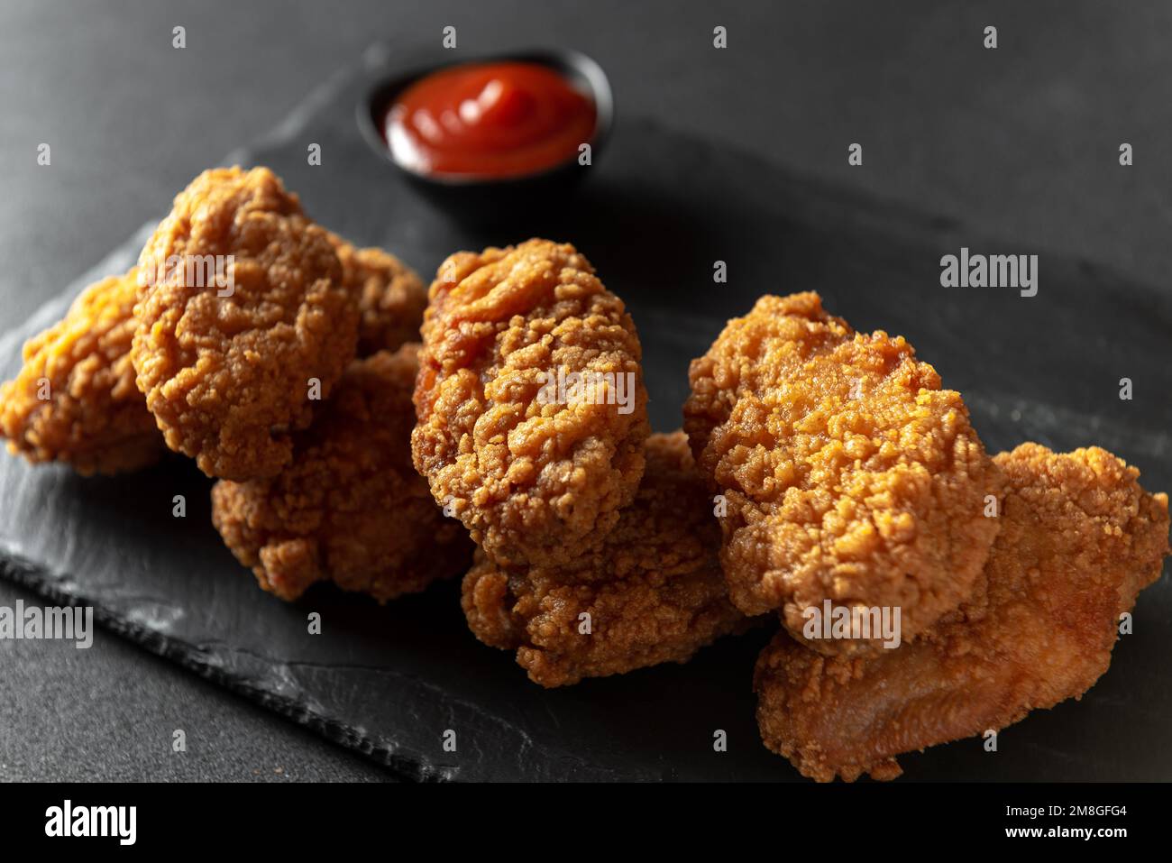 Fried chicken fillet on a dark background. Fried chicken wings as in