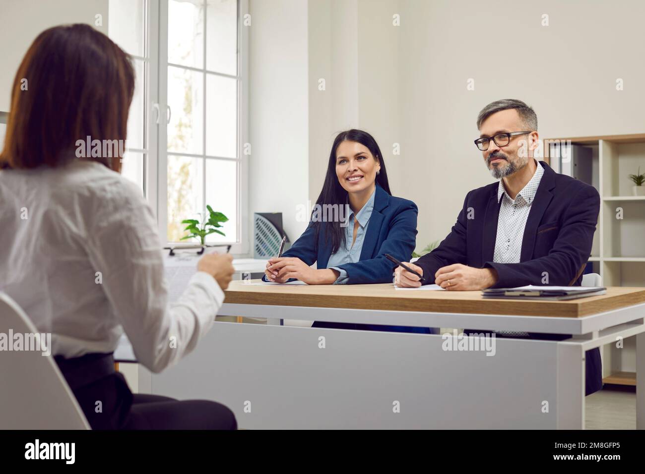 Two human resources workers listen as female job candidate talks about her work experience. Stock Photo