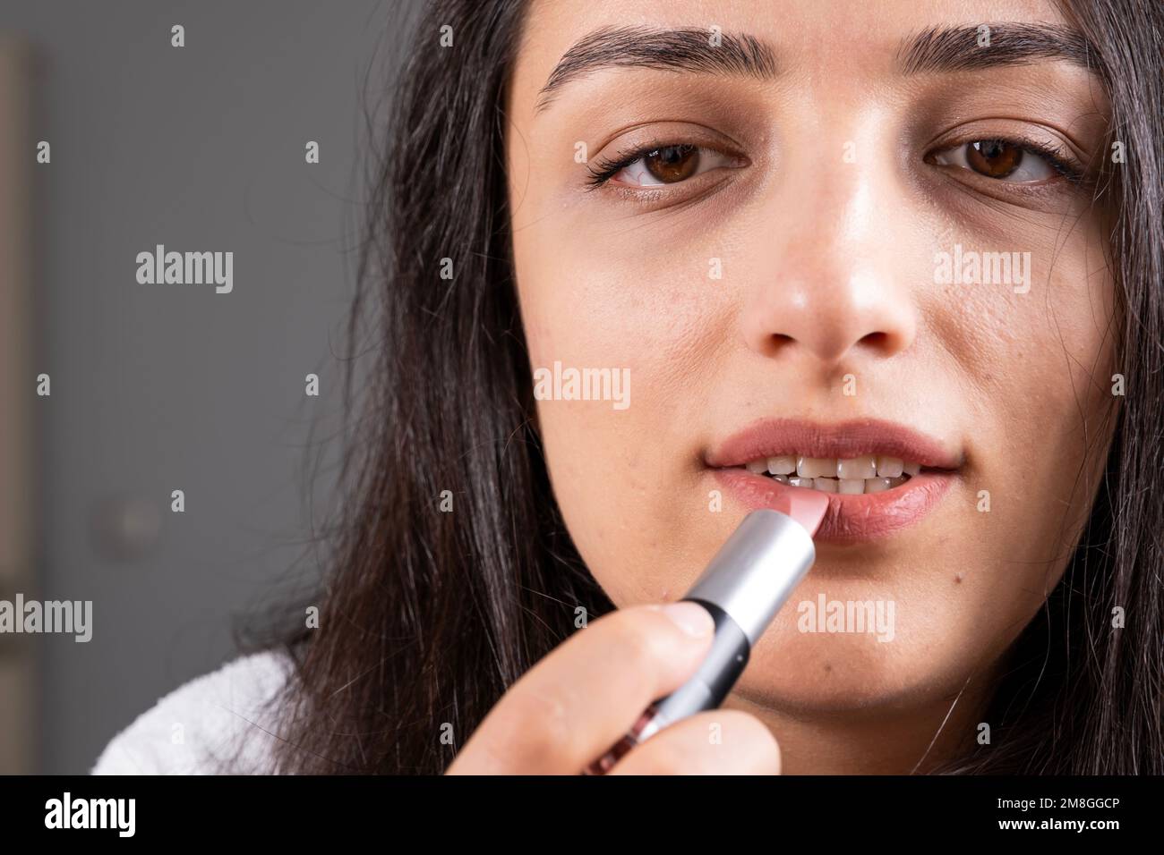 Close up image of woman holds lipstick. Rouging color on lips. Applying make up using professional cosmetics. Morning beauty routine of modern girl. Stock Photo
