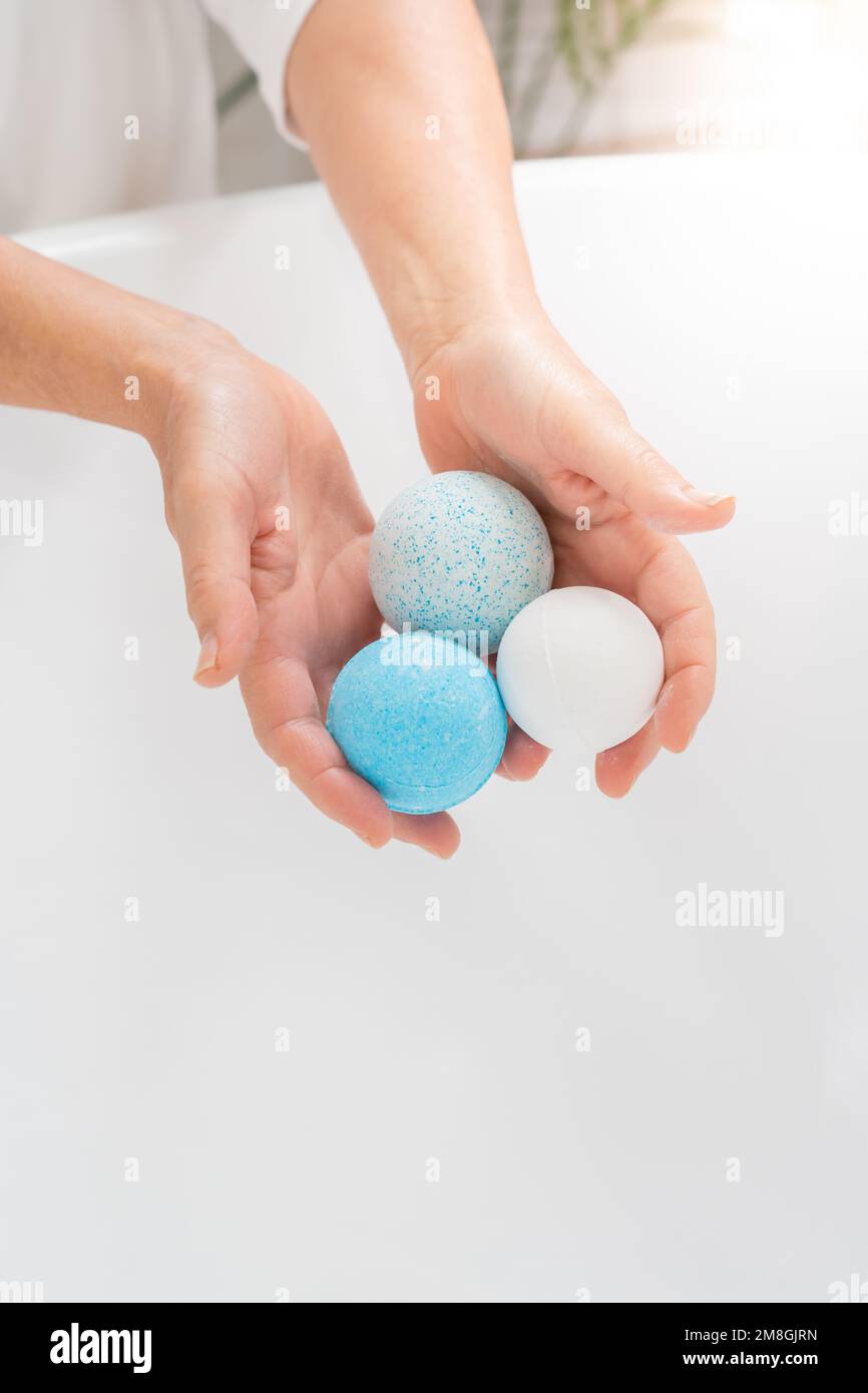 Vertical closeup of a woman's hands putting salt and soap balls in the