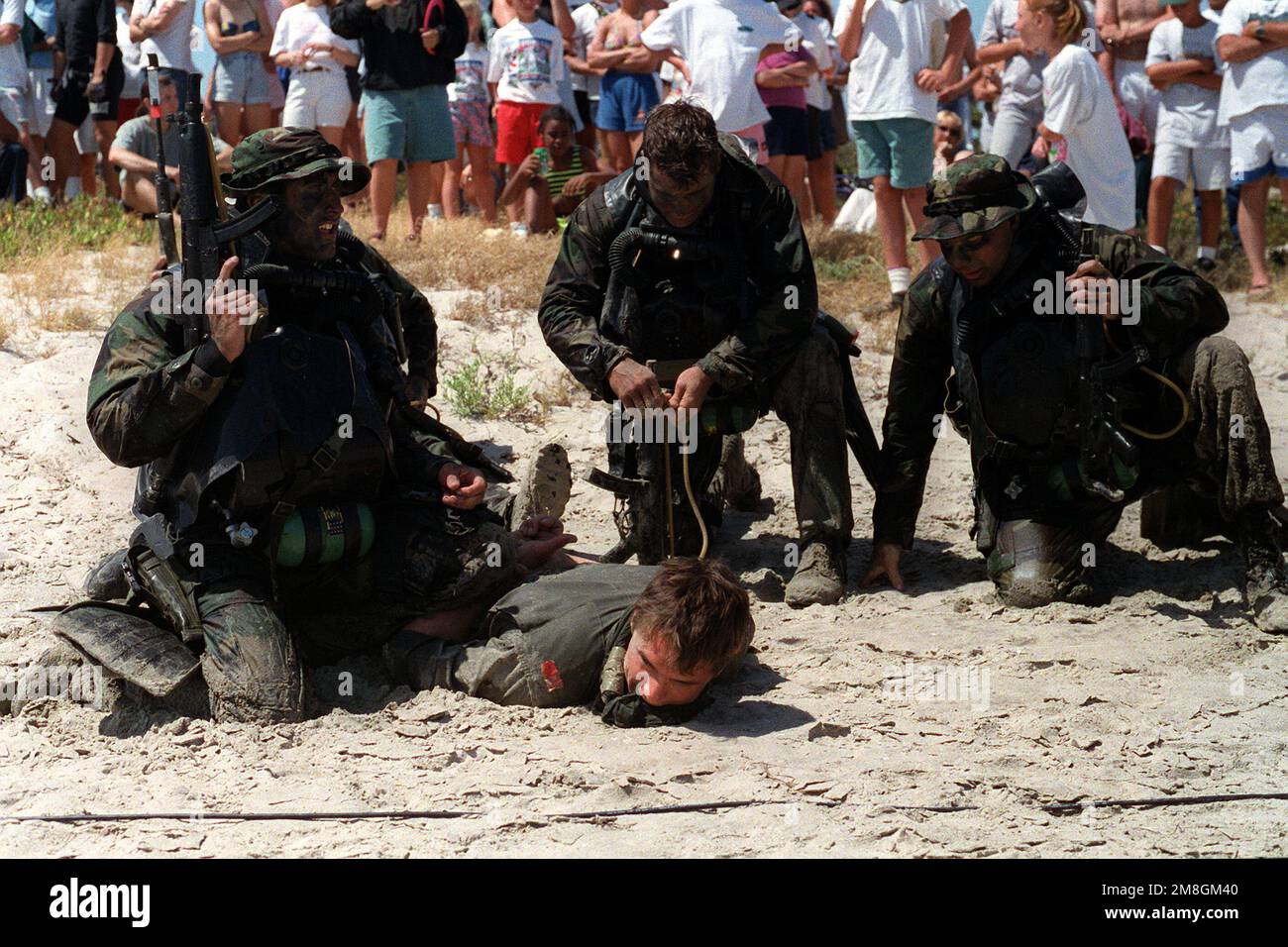 Members of a U.S. Navy Sea-Air-Land (SEAL) team secure a prisoner during a public demonstration. The SEALs are armed with 9mm MP5 sub-machine guns. Base: Coronado State: California (CA) Country: United States Of America (USA) Stock Photo