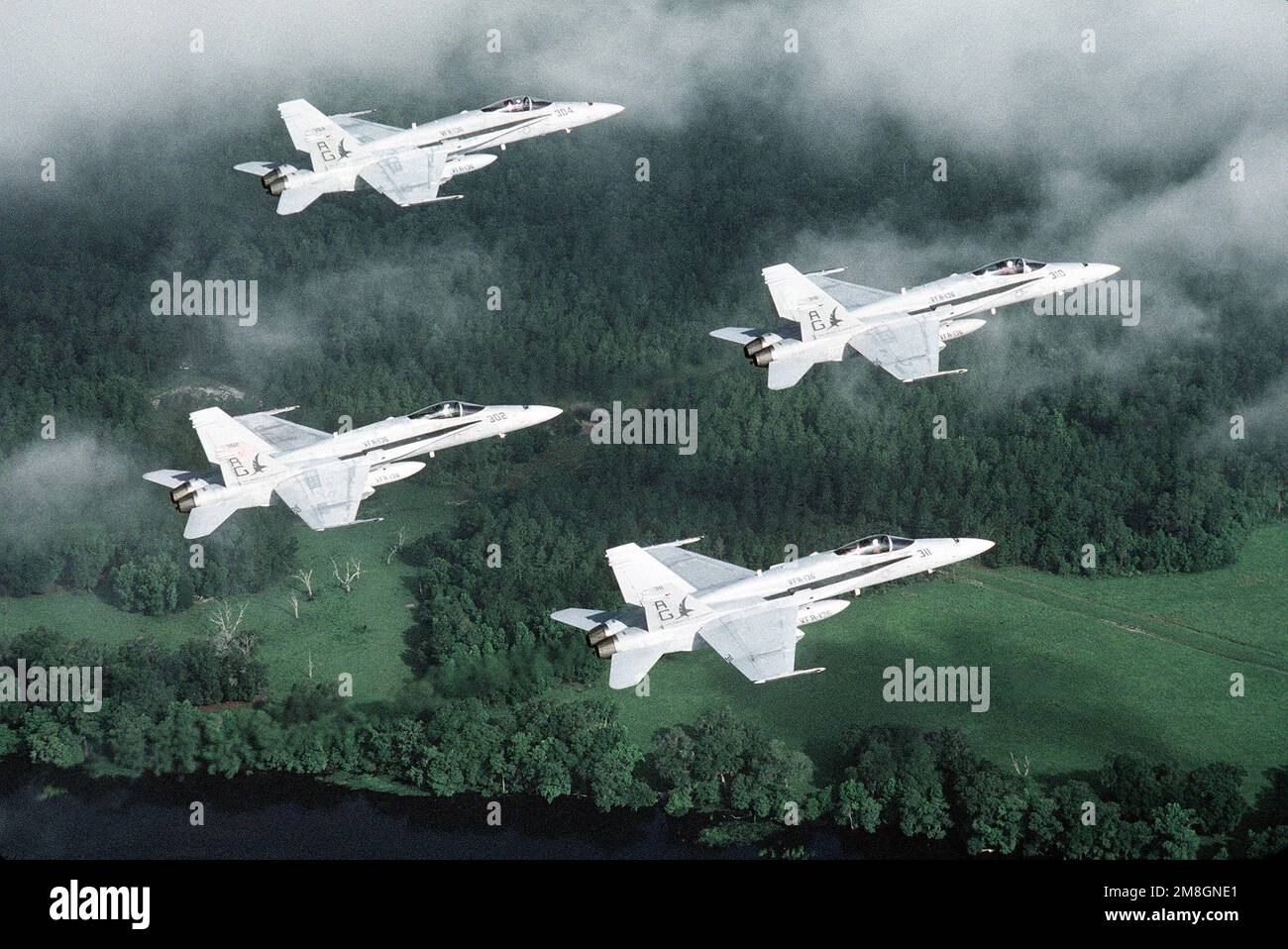 An air-to-air, right side view of four Strike Fighter Squadron 136 (VFA-136) F/A-18C Hornet aircraft flying in a diamond formation. Country: Unknown Stock Photo