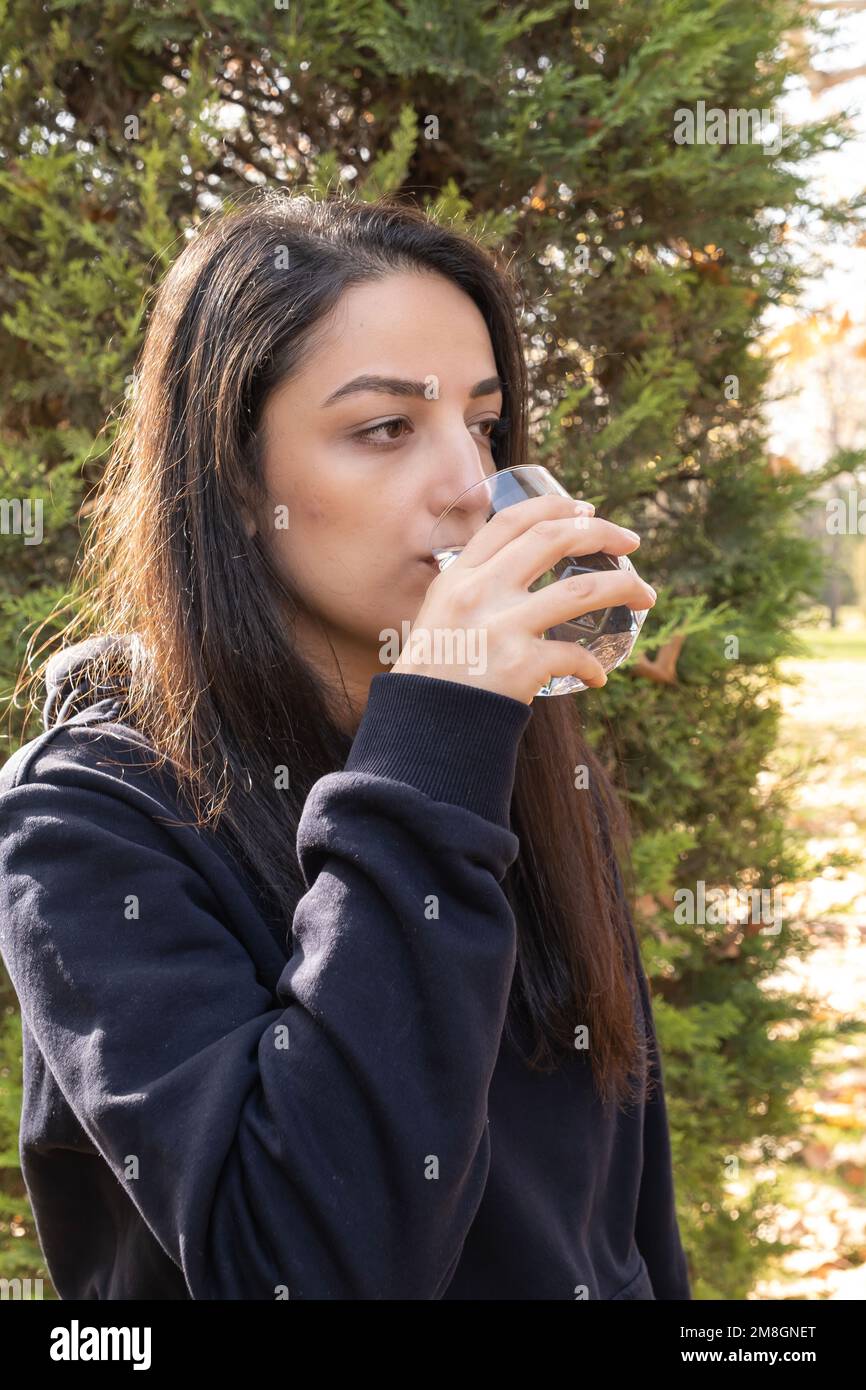 Thirsty woman drinking water from glass. Vertical image of caucasian girl recoveries hydration balance. Healthy lifestyle concept idea. Stock Photo