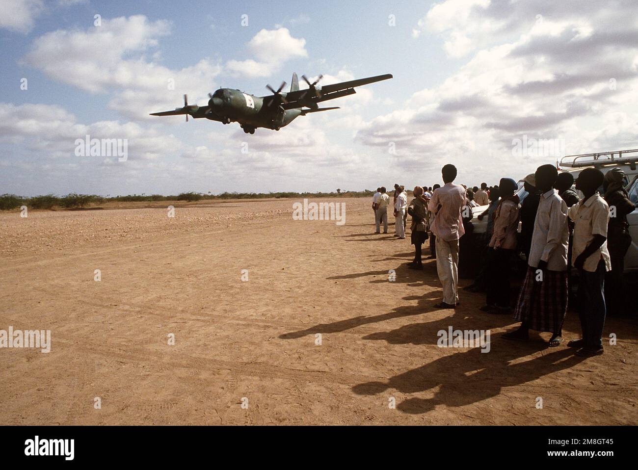 Local Kenyan workers watch a C130 Hercules from the 314th Air Lift