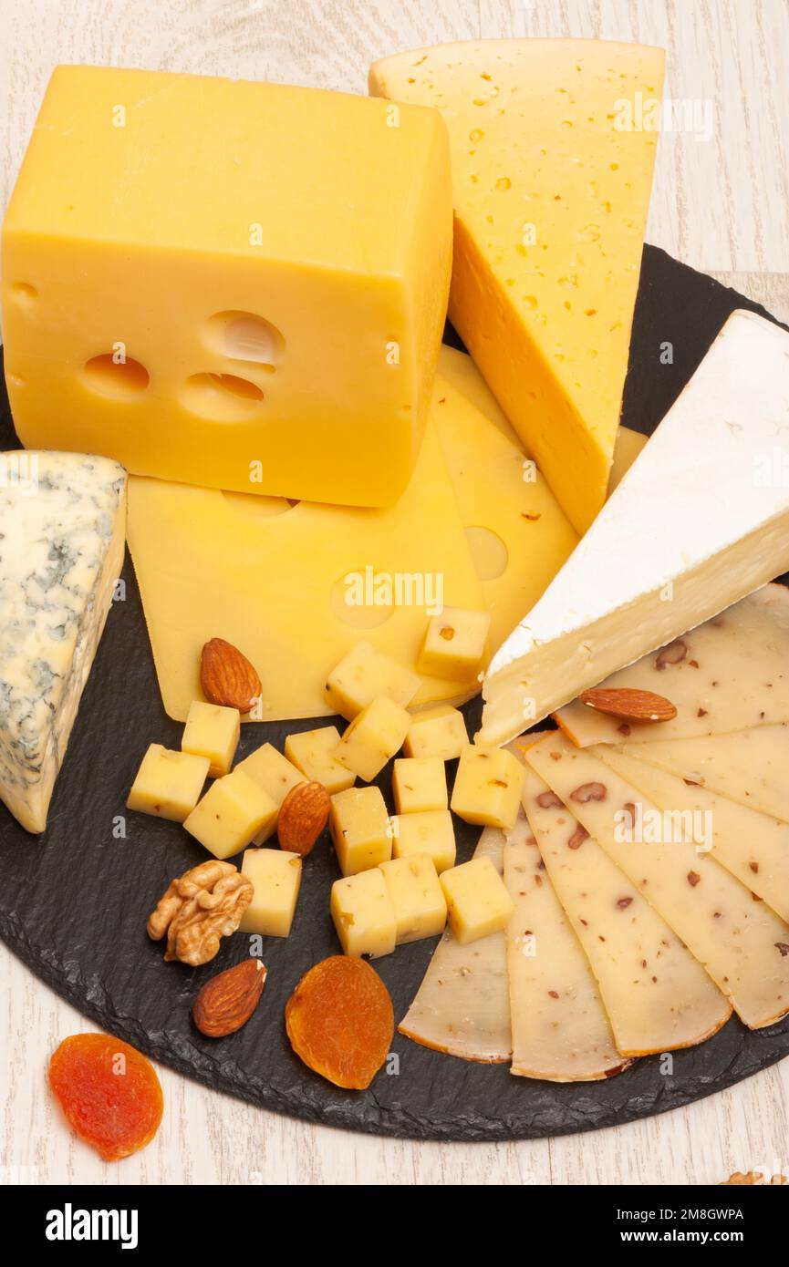 Different types of cheese on a black graphite board decorated with