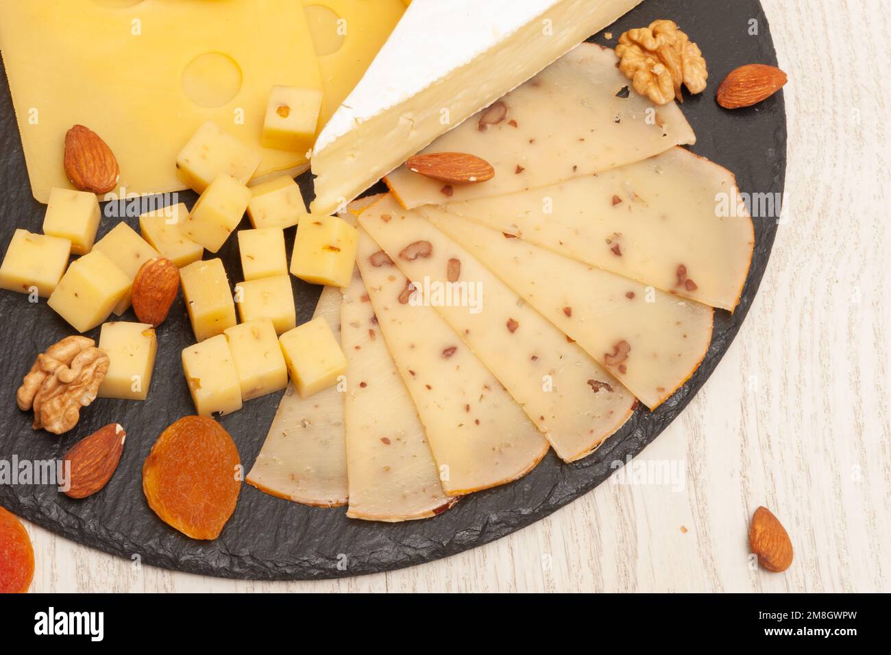 Different types of cheese on a black graphite board decorated with