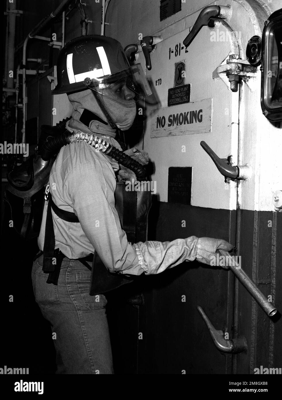 A fireman wearing oxygen breathing apparatus opens a compartment during
