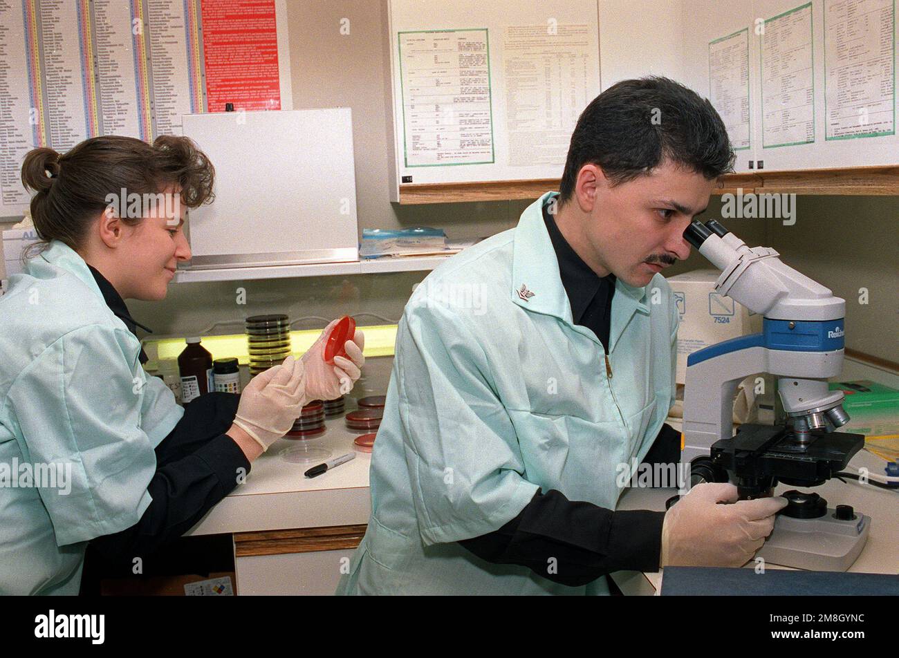 Hospital Corpsman Third Class (HM3) K. Bonitch, left, places a specimen