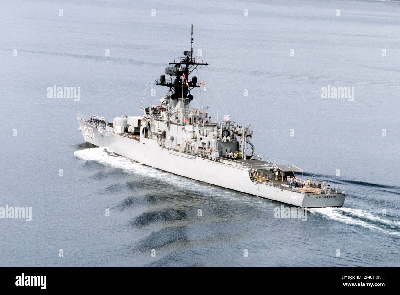 Members of the deck force stand in formation on the deck of the frigate