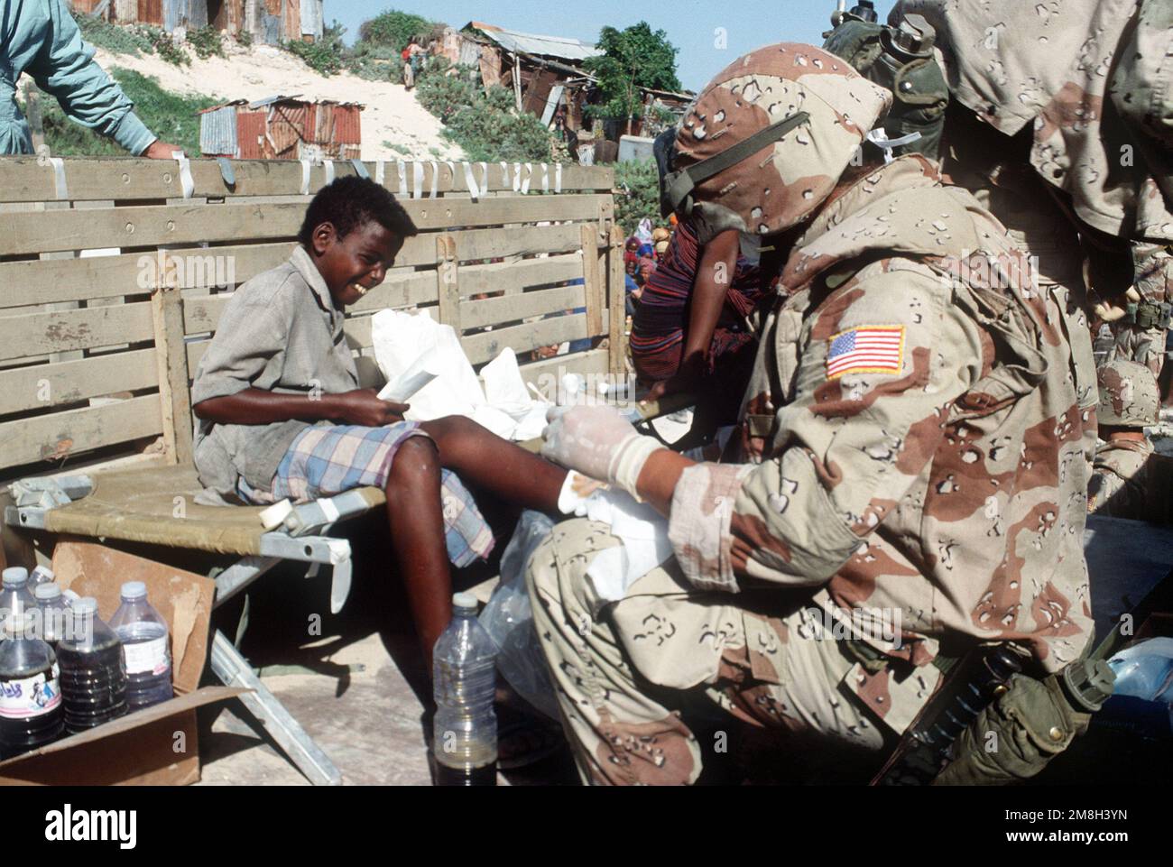 A Navy corpsman serving with Combat Service Support Detachment 15 (CSSD-15) treats a Somali girl's infected foot. He is participating in a medical civic action program being conducted during the multinational relief effort Operation Restore Hope. Subject Operation/Series: RESTORE HOPE Base: Modadishu Country: Somalia (SOM) Stock Photo