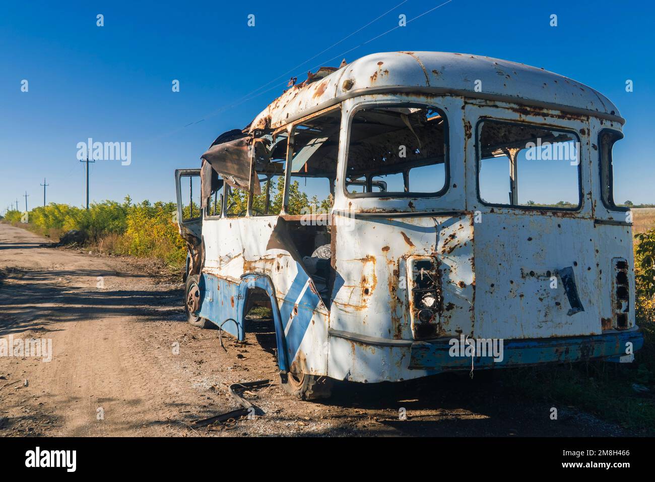 Damaged bus after shelling. War in Ukraine. Russian invasion of Ukraine. Countryside. Terror of the civilian population. War crime Stock Photo