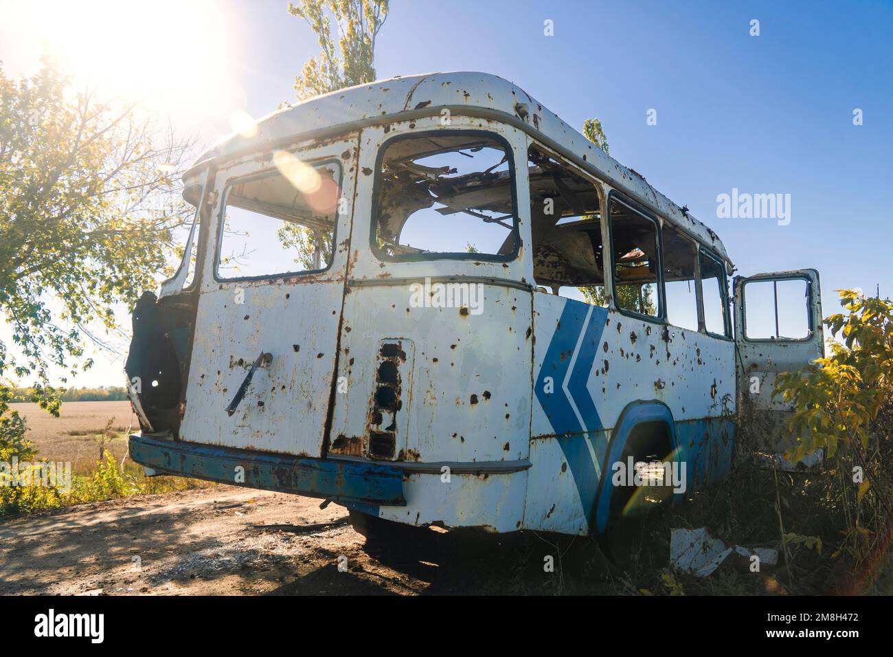 Damaged bus after shelling. War in Ukraine. Russian invasion of Ukraine. Countryside. Terror of the civilian population. War crime Stock Photo