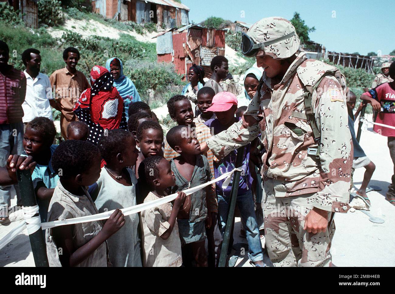 A Marine talks with a group of Somali boys who are waiting to be examined by a Navy corpsman. Combat Service Support Detachment 15 (CSSD-15) is conducting a medical civic action program in the streets of the city during the multinational relief effort Operation Restore Hope. Subject Operation/Series: RESTORE HOPE Base: Mogadishu Country: Somalia (SOM) Stock Photo