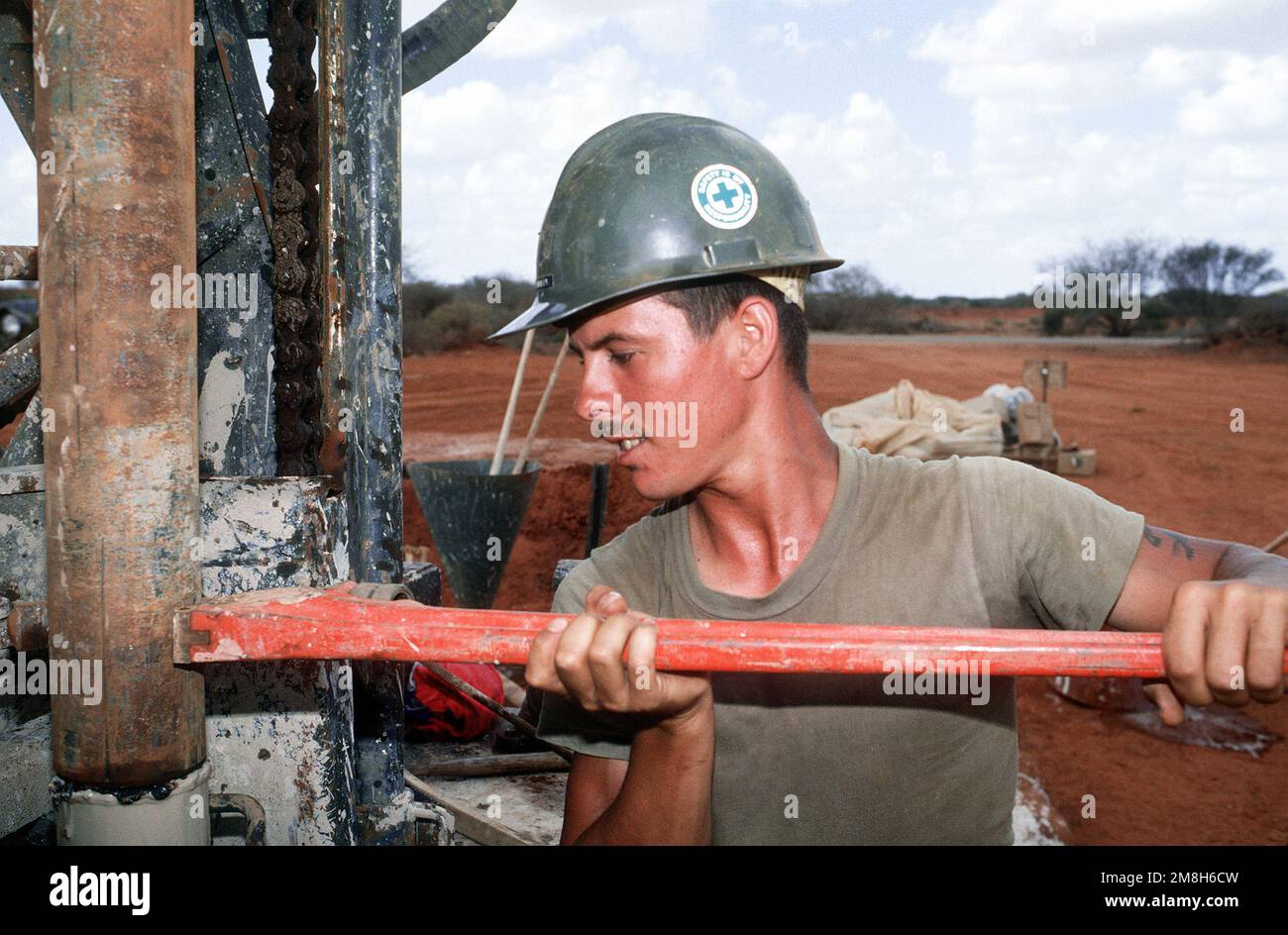 A member of Naval Mobile Construction Battalion 1 (NMCB-1) tightens a fitting on a well drilling rig during the multinational relief effort Operation Restore Hope. The water well, near Bale Dogle, is intended to supply an old Soviet air base being used by U.S. and Moroccan personnel participating in the operation. Subject Operation/Series: RESTORE HOPE Country: Somalia (SOM) Stock Photo