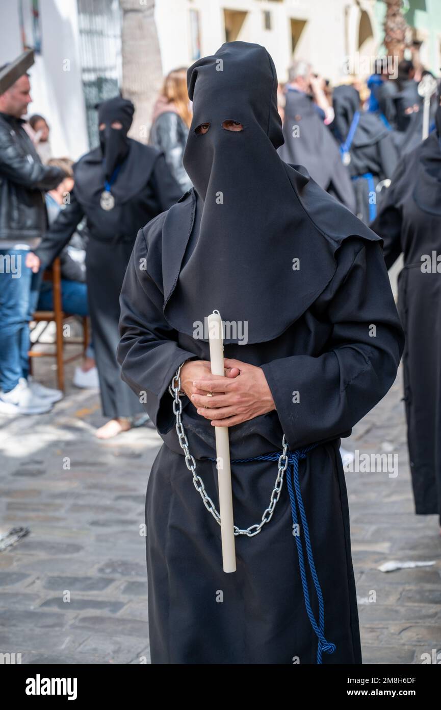 People wearing black clothing and chains walking barefoot in a traditional Easter parade at Holy week or semana santa in Cadiz Spain Stock Photo