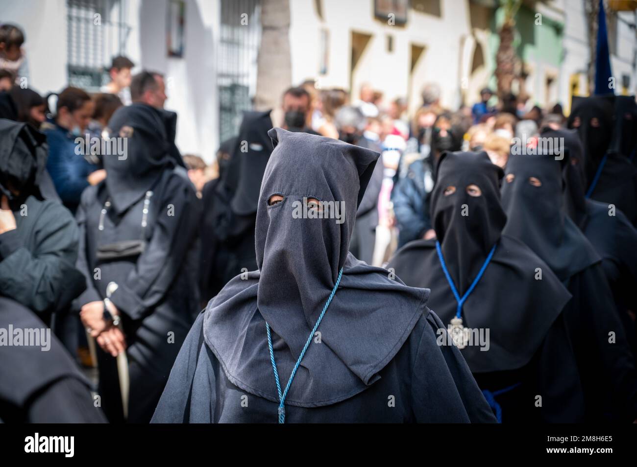 People wearing black clothing and chains walking barefoot in a traditional Easter parade at Holy week or semana santa in Cadiz Spain Stock Photo