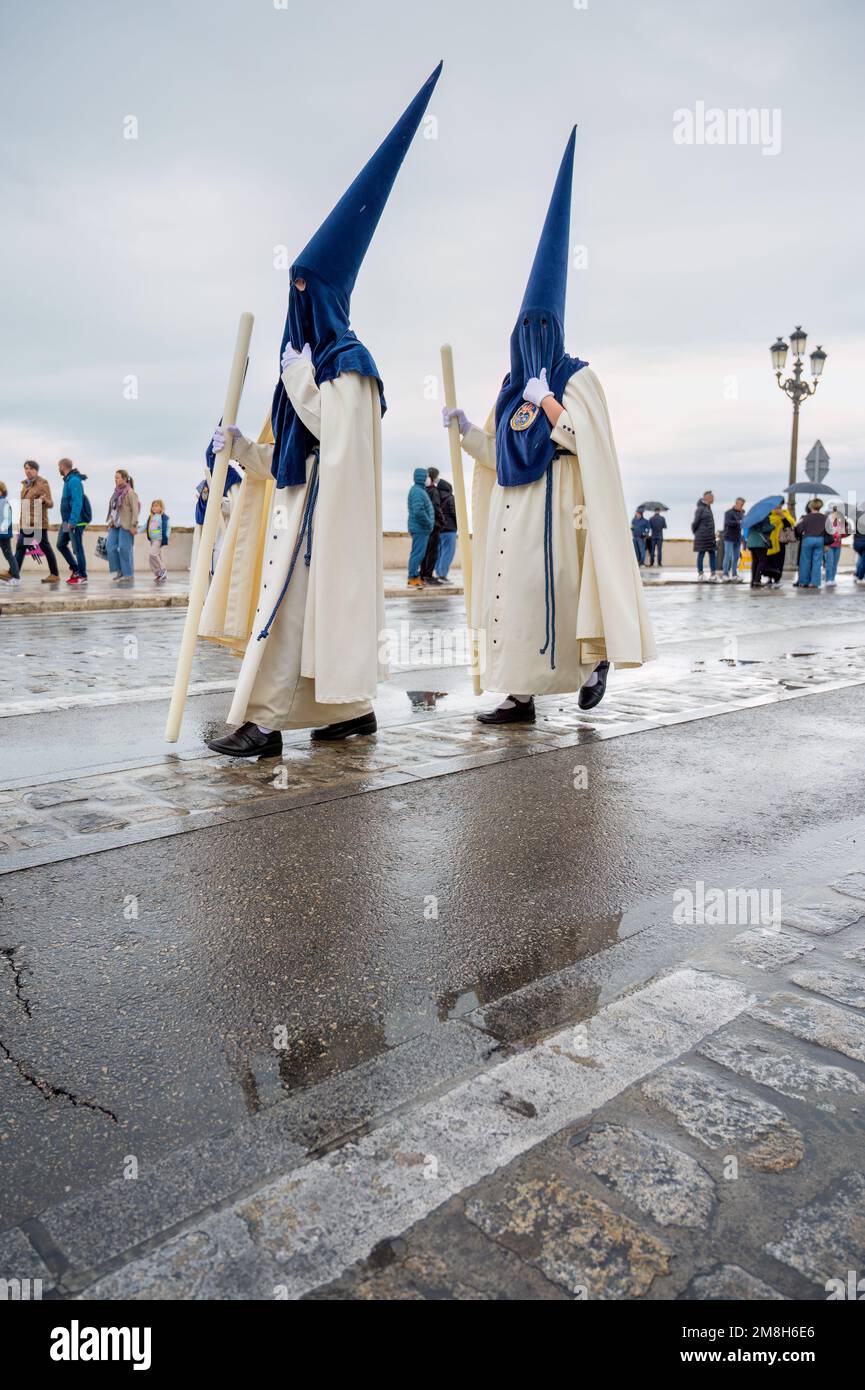 People in traditional dress weraing a capriote, or pointed hat in an Easter Parade during Holy Week or Semana Santa in Cadiz, Spain Stock Photo