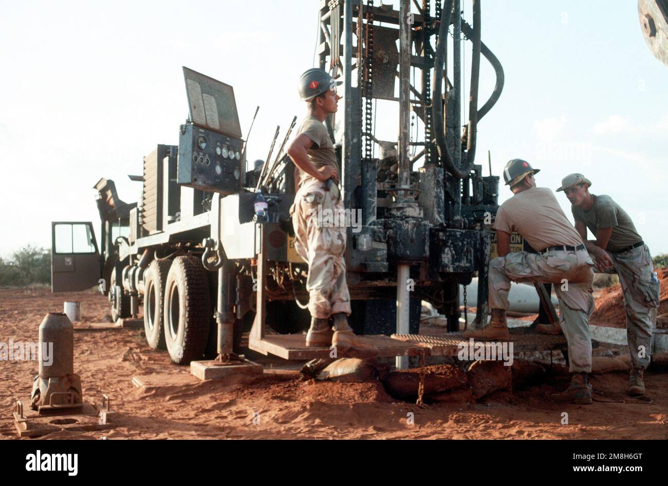 Members of Naval Mobile Construction Battalion 1 (NMCB-1) take a break while working on a mobile drilling rig being used to drill a water well. The well, near Bale Dogle, is intended to supply an old Soviet air base being used by U.S. and Moroccan personnel participating in the operation. Subject Operation/Series: RESTORE HOPE Country: Somalia (SOM) Stock Photo