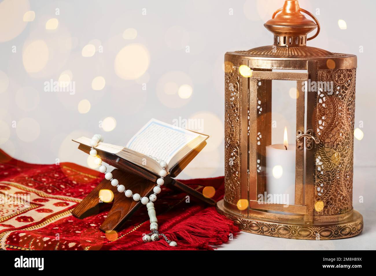 Muslim lantern with Quran, prayer mat and tasbih on light background