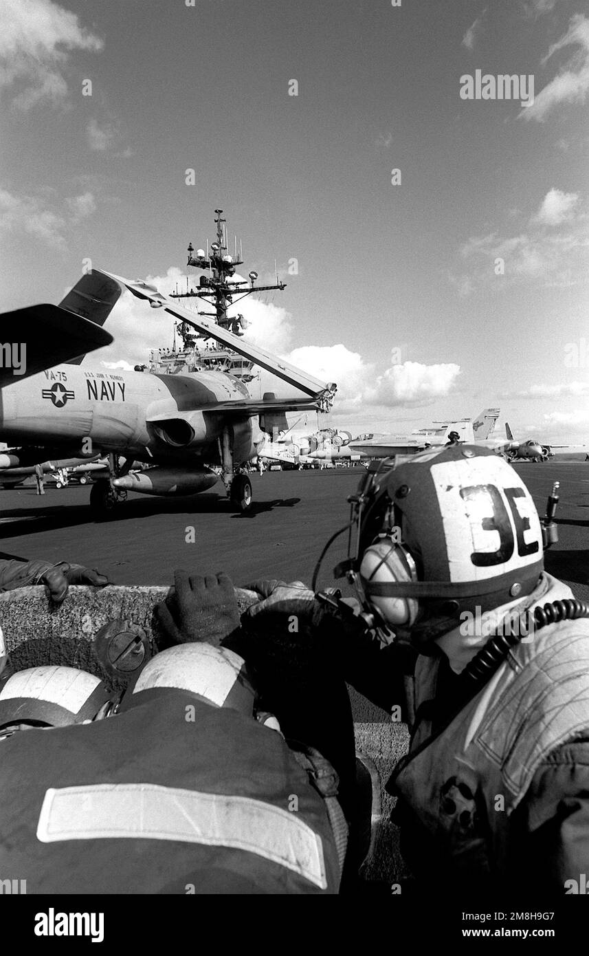 Catapult crew members take cover as an Attack Squadron 75 (VA-75) A-6E Intruder aircraft passes by during flight operations on the flight deck of the aircraft carrier USS JOHN F. KENNEDY (CV-67). Country: Adriatic Sea Stock Photo